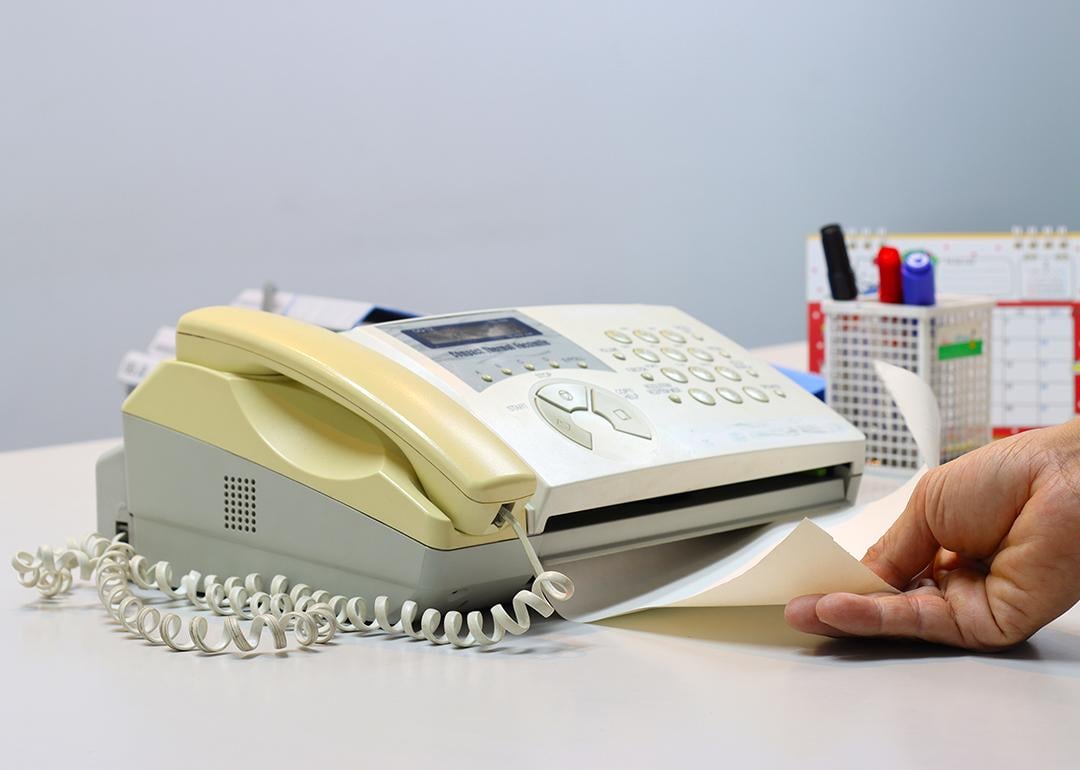 Person feeding a yellowing fax machine paper.