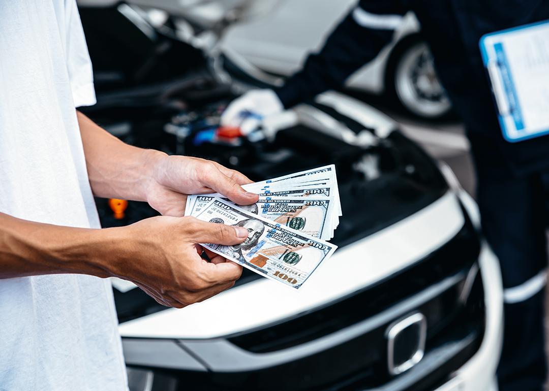 Customer pays with cash to the car mechanic after a service.