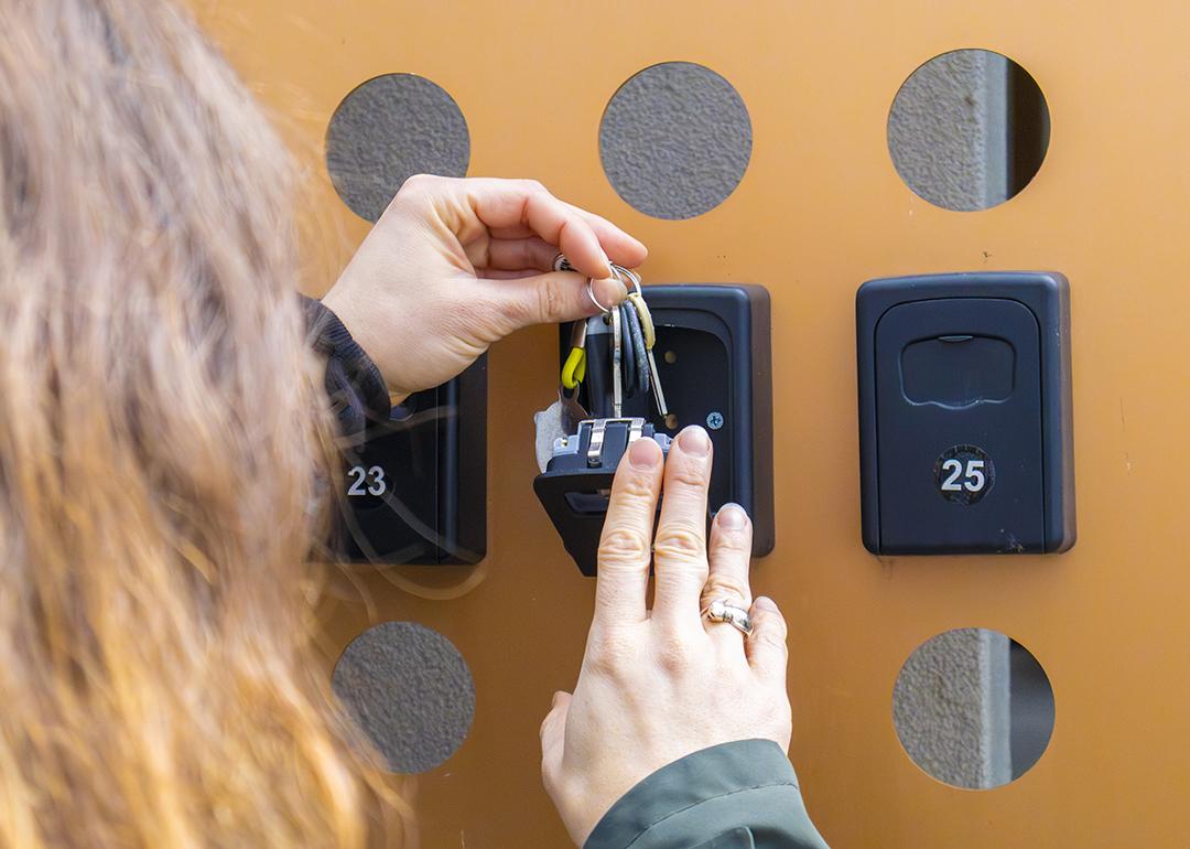 A person putting keys inside an apartment key box.