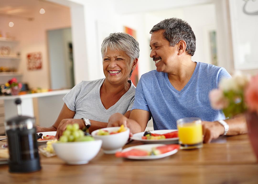 A retired senior couple happily having breakfast at home.
