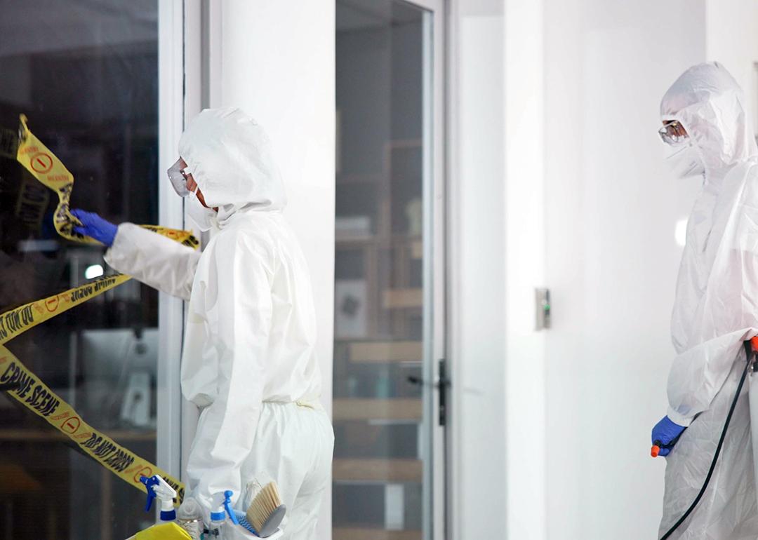 A forensic team removing a barrier tape from a crime scene.