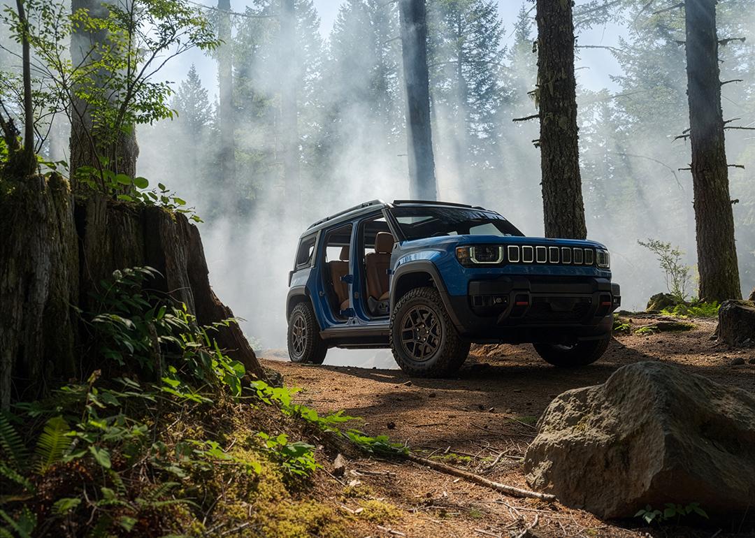 Low angle view of a Blue Jeep Recon Moab parked in a forest with mist rising in the background.