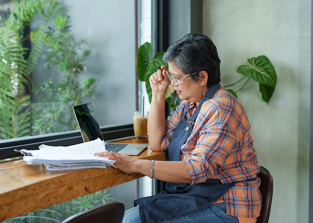 A senior small businesswoman reviewing reports by the window of her store.