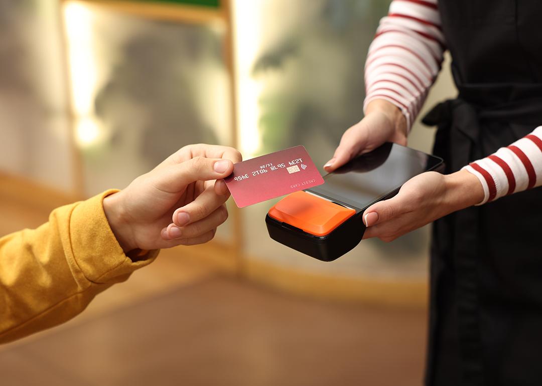 A person paying with a credit card payment machine held by a cafe staff.