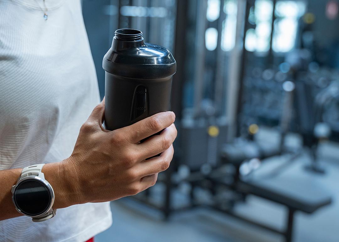 A person holding a water bottle during her workout in a gym. 