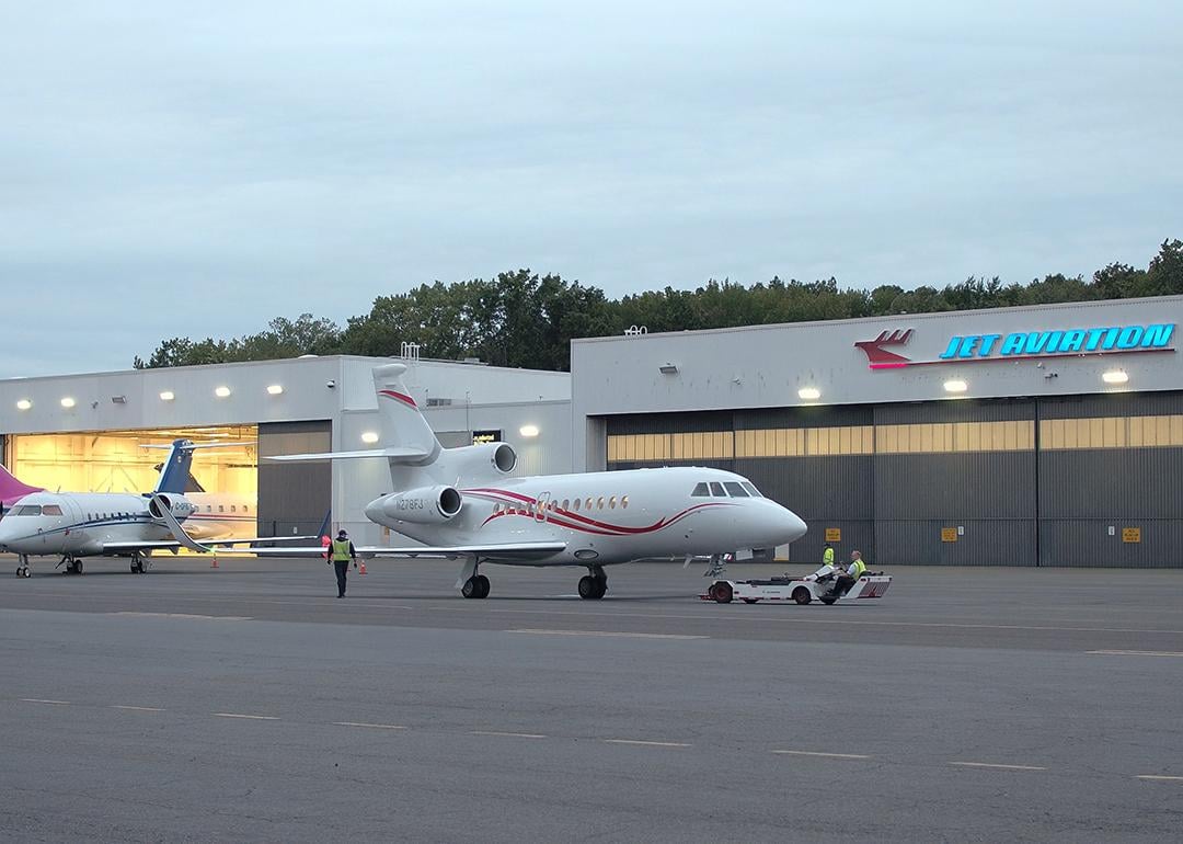 Line technicians working at the Teterboro Airport, operating aircraft towing vehicles and parking airplanes in the hangar.