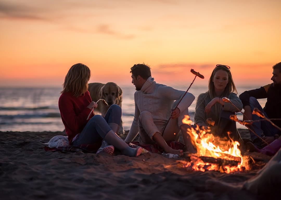 A group of friends sitting around a campfire by the beach.