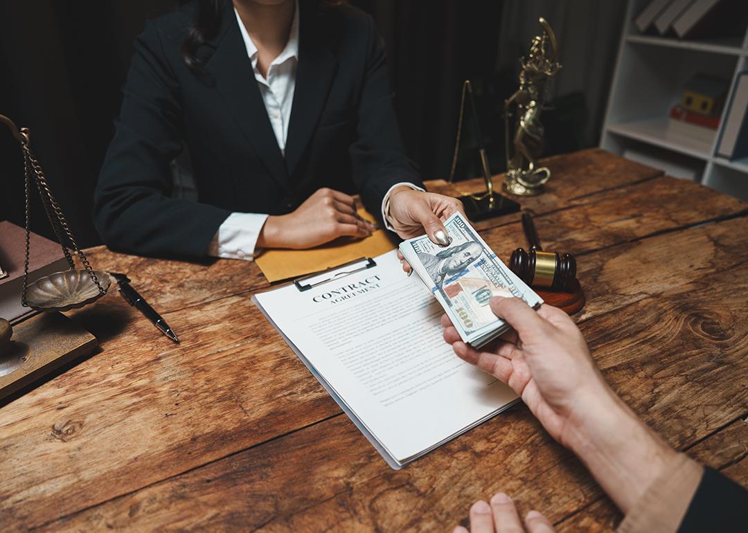 A legal professional accepting cash from a client over a contract agreement.
