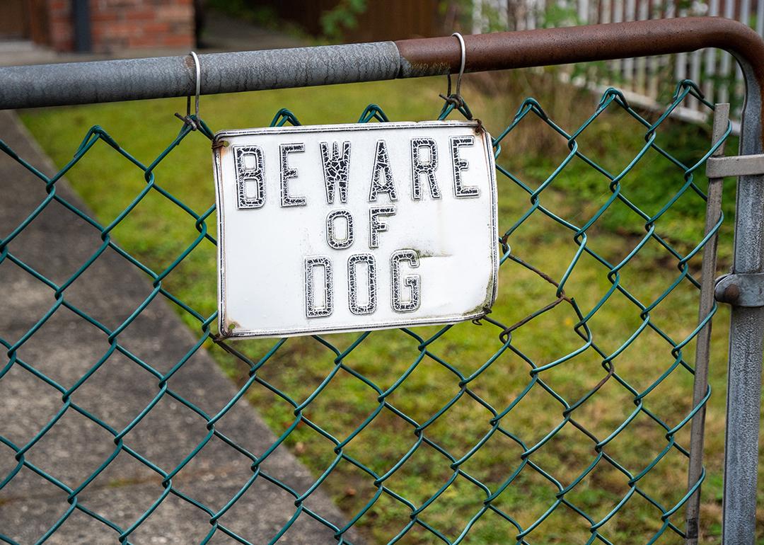 A Beware of Dog sign hung to a house's gate.