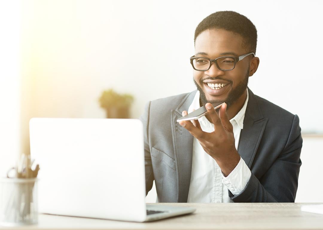 A happy young black businessman using voice assistant on his smartphone.