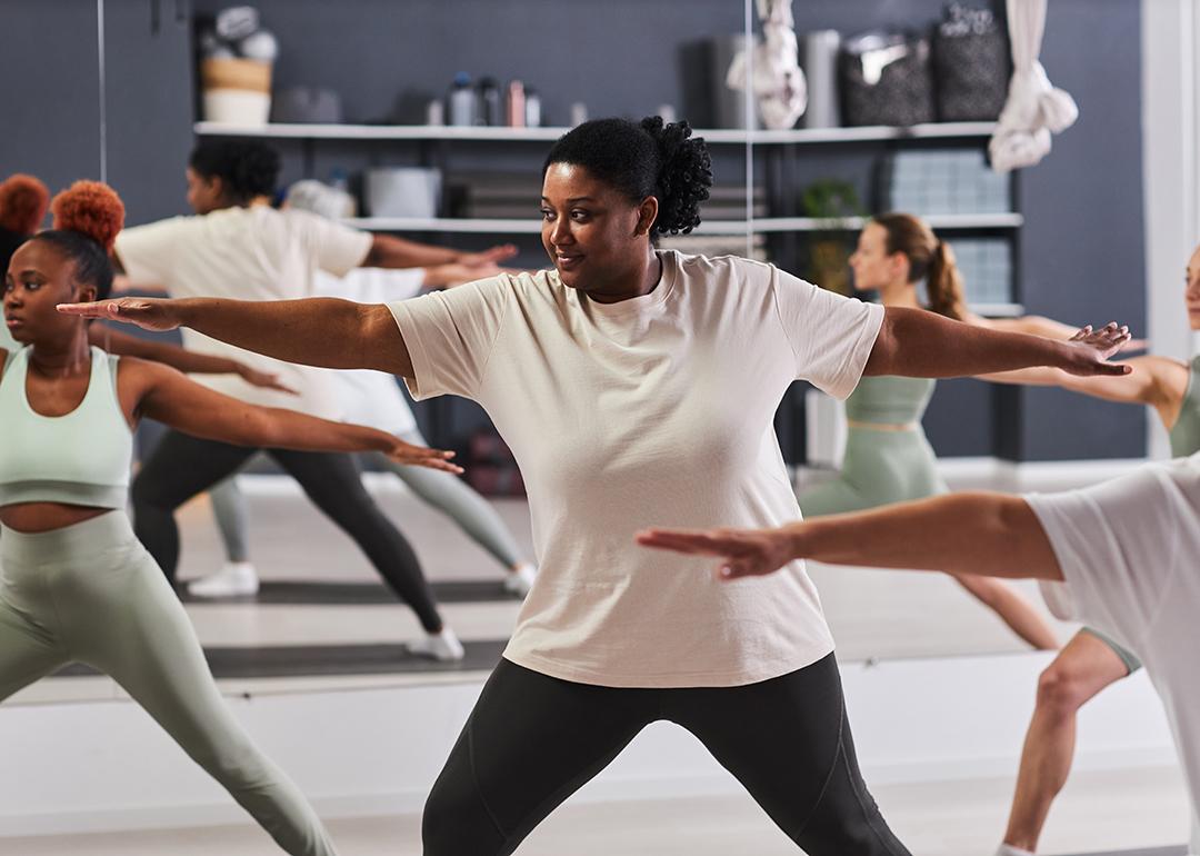 Focus on a black woman among a group doing aerobics together in a studio.