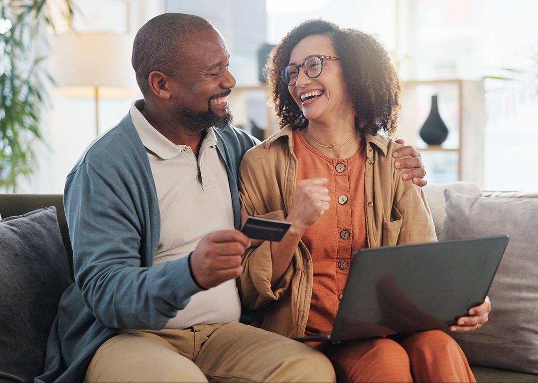 A happy couple at home purchasing online with a credit card.