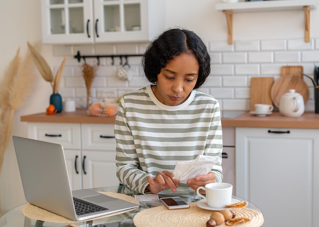A young woman at home calculating expenses.