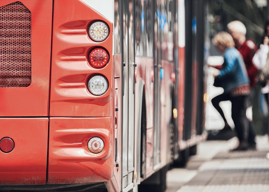Rear view of a public transport bus at a stop with passengers entering.