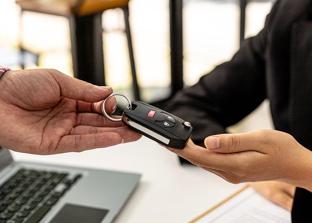 A person returning a car key to an employee for completing a car rental service.