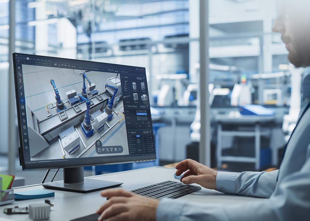 A factory engineer works with an advanced 3D CAD software to model robotic assembly line.