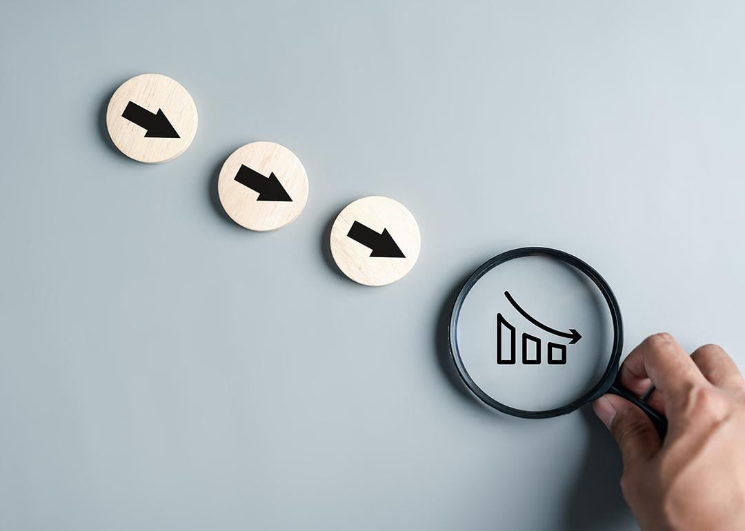 Downward arrows and a magnifier focused on a declining chart as a concept of inflation.