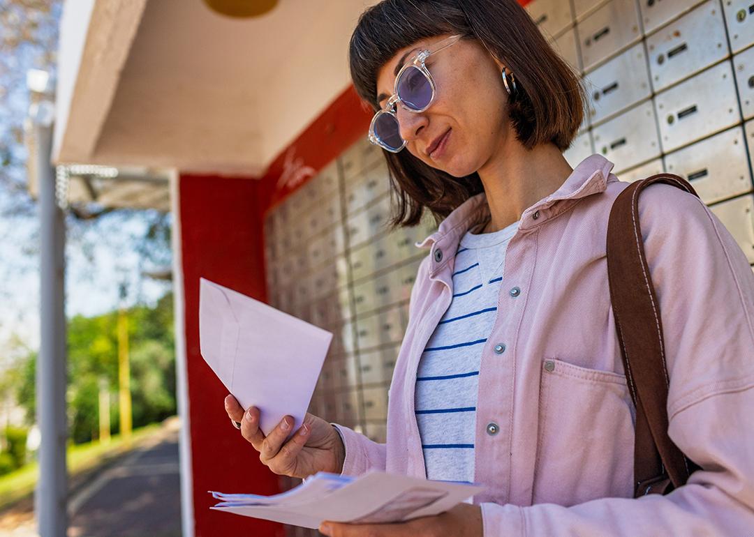 A young woman checking letters from mailbox.