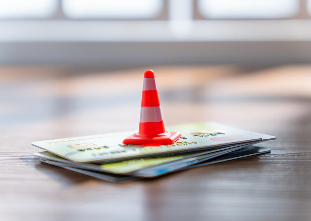 A traffic cone on a stack of credit cards. 