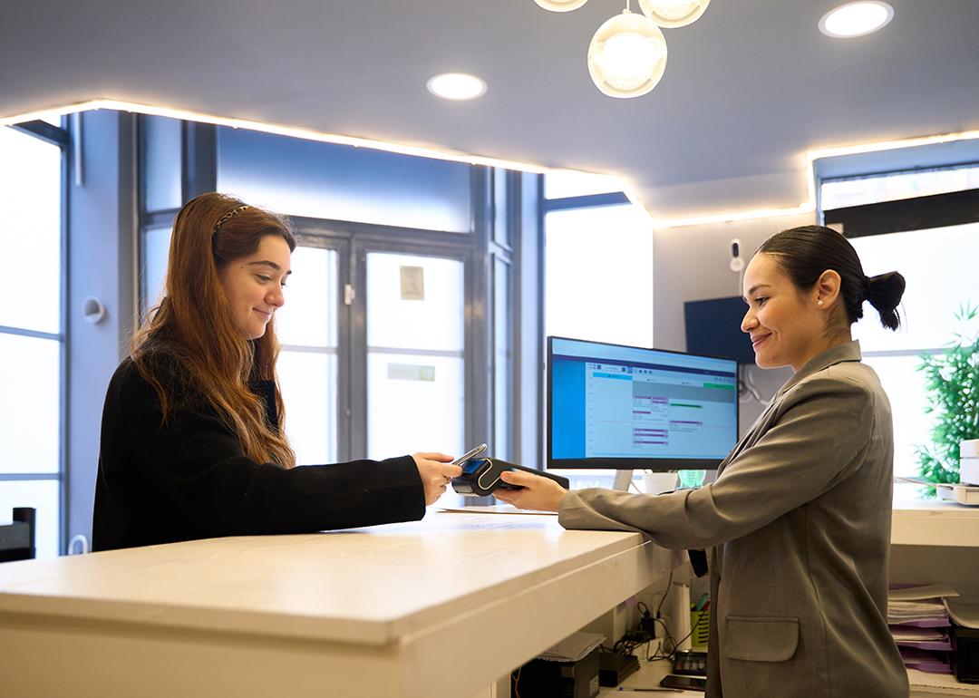 Patient making a contactless payment at a clinic's reception desk.