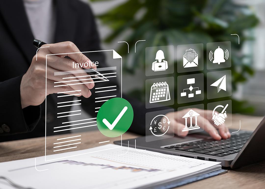Automated invoice software graphics over a businessperson using a laptop.
