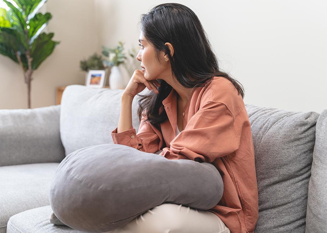 Stressed young woman at home sitting on a sofa.