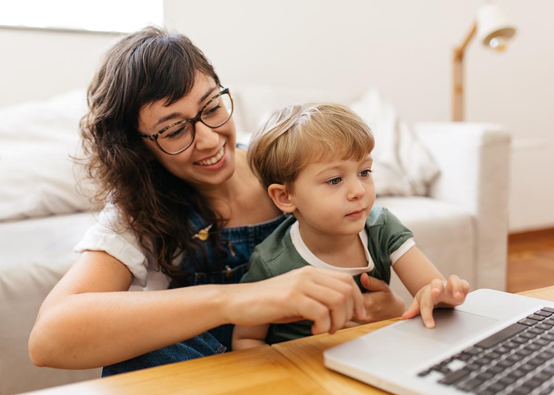 A mother and a son checking on a laptop in a living room.