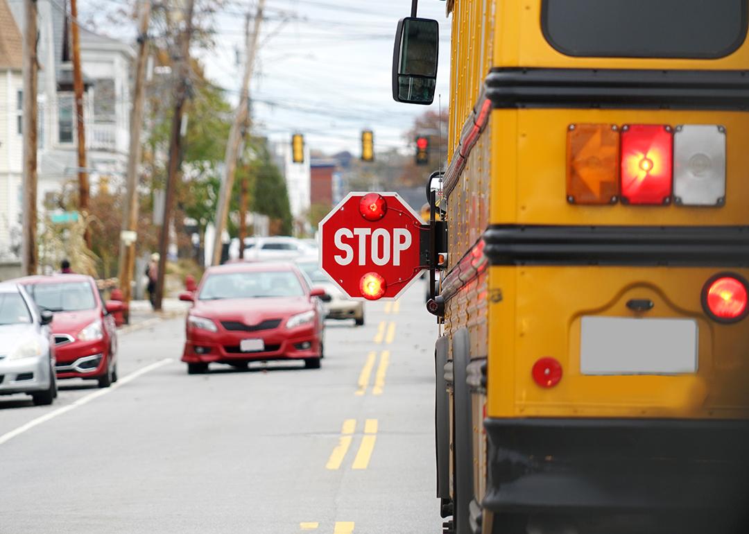 Rear view of a school bus with a 'stop' sign being held by its driver.