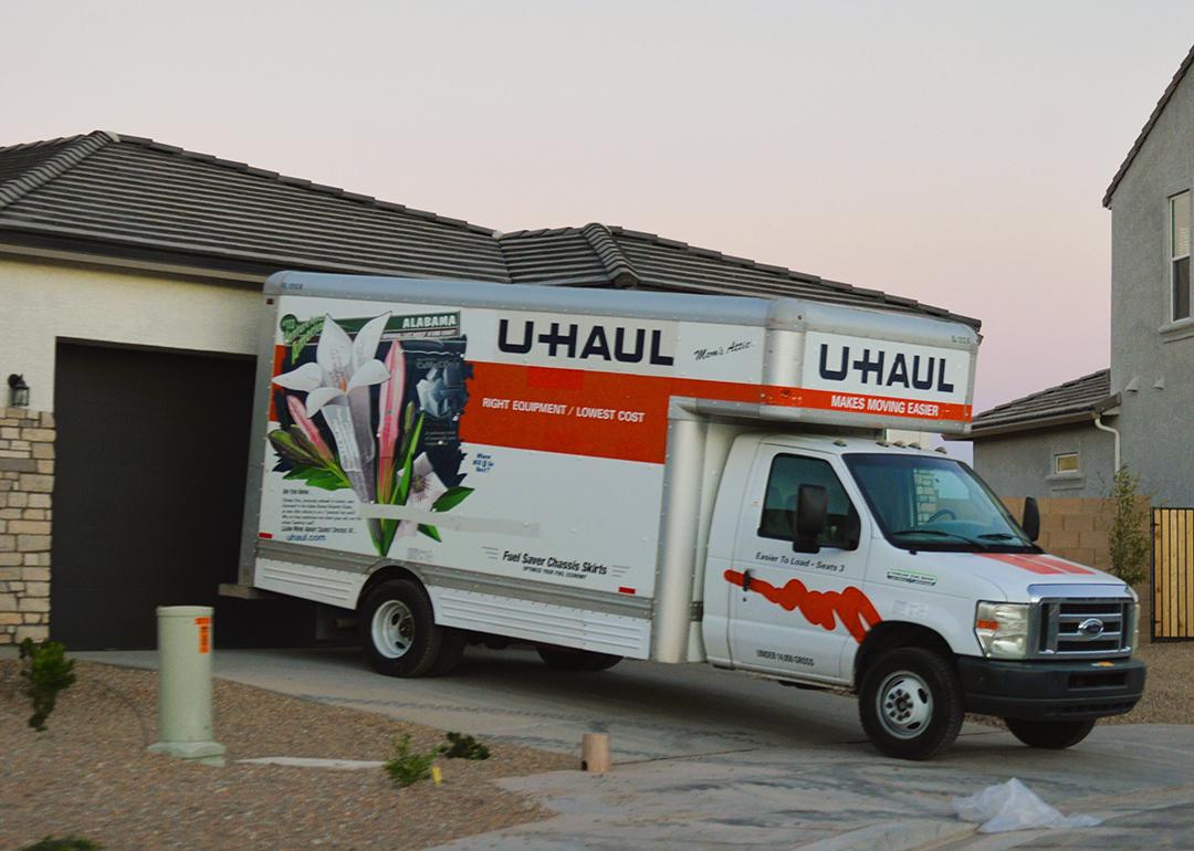 A U-Haul moving van parked in front of a newly built home.