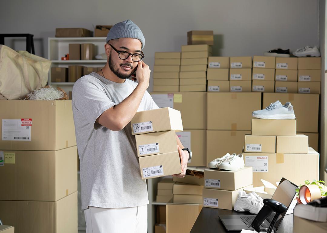 A male e-commerce shoe business owner on the phone while assembling orders.