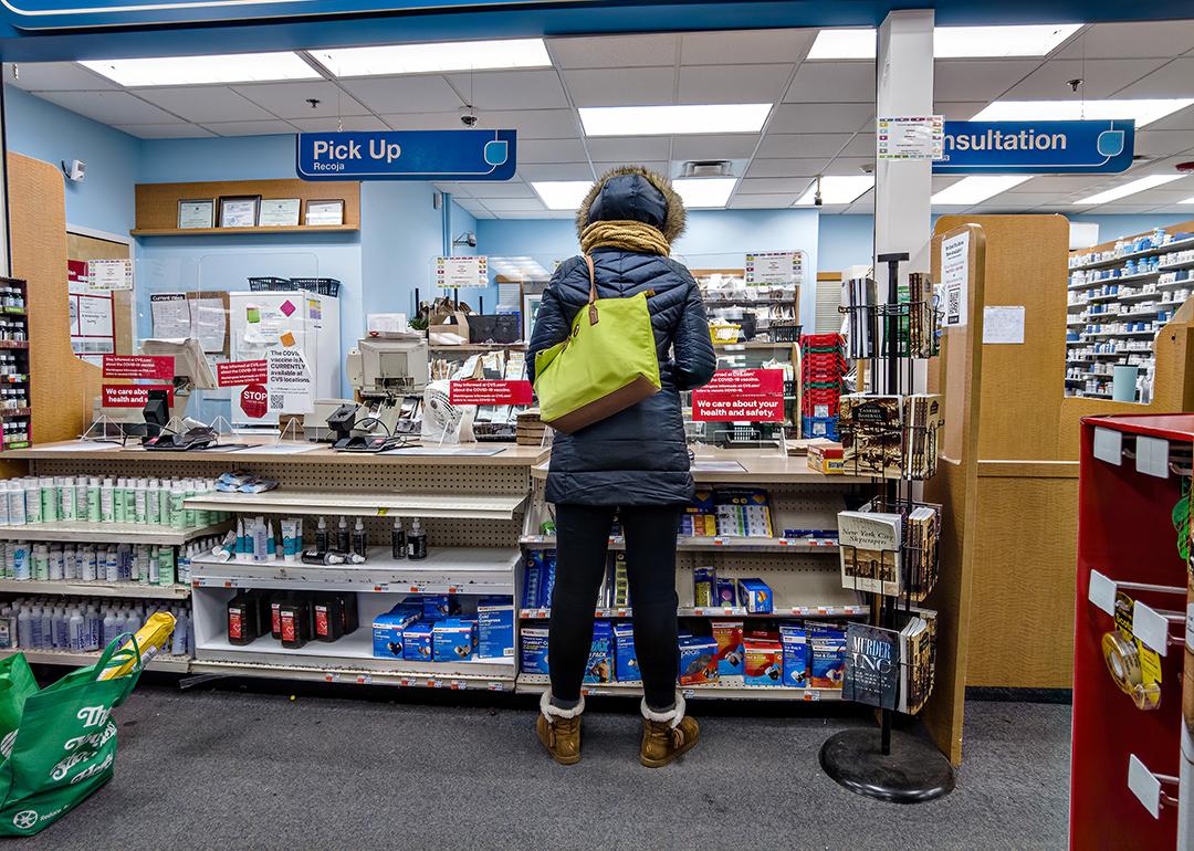 Woman in a winter coat purchasing medication at a CVS pharmacy counter.