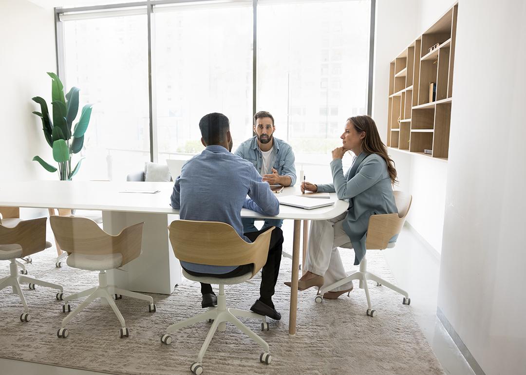 A three-member business team brainstorming inside a meeting room.