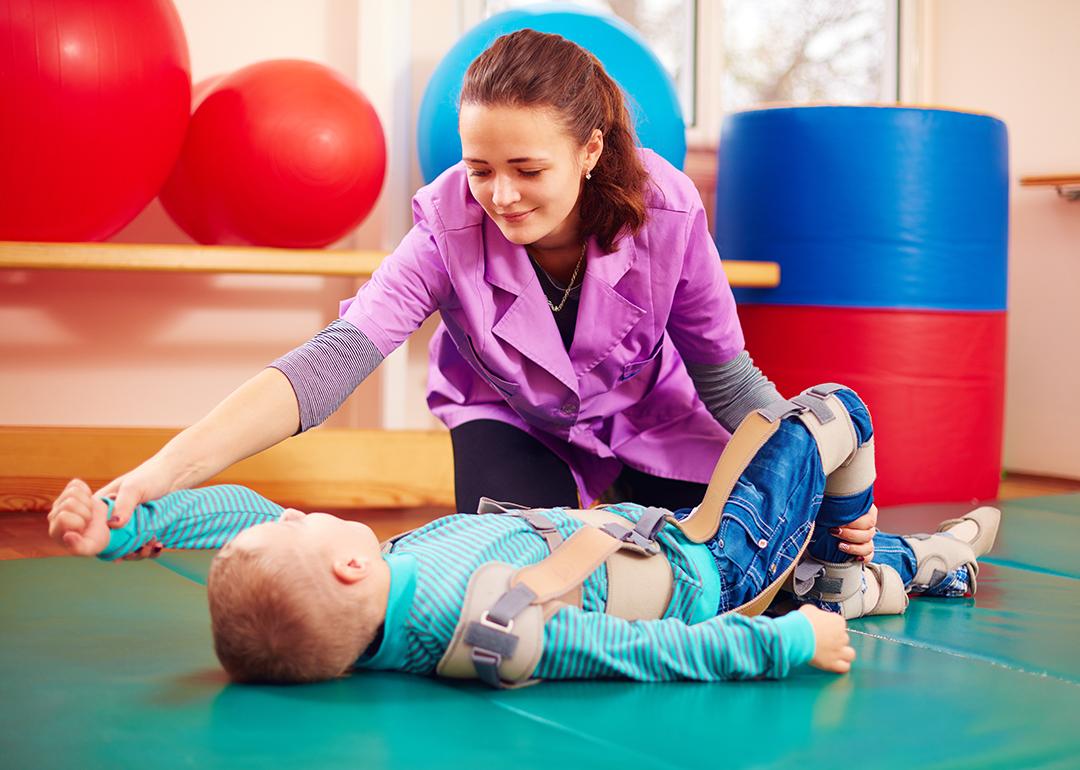 A pediatric therapist helping a young boy with a musculoskeletal therapy exercise.