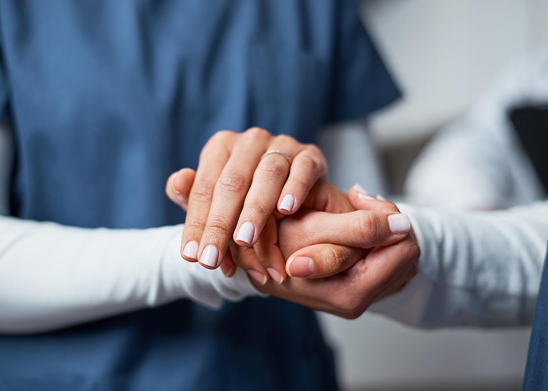 A nurse compassionately holding hand of a patient.