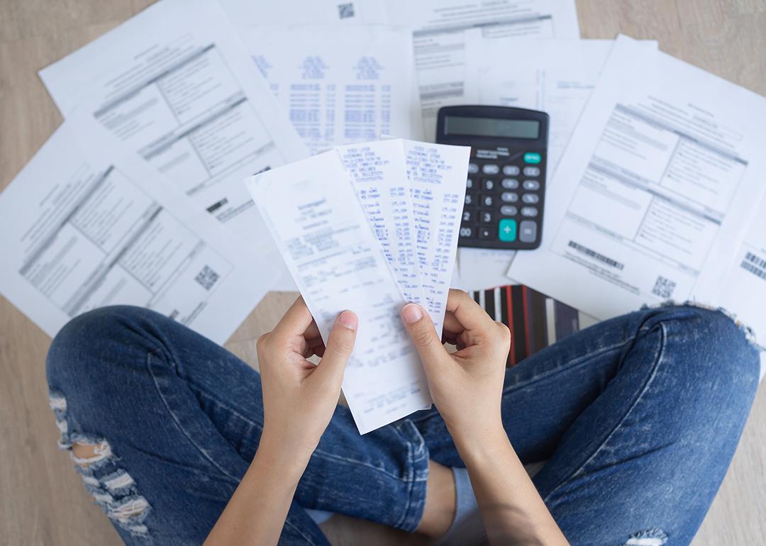 Person arranges bills and expenses on the floor.