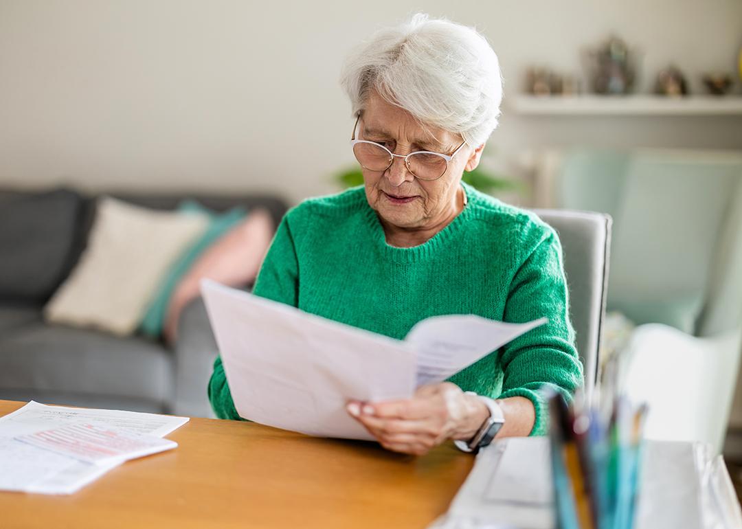 A senior woman sitting in the living room and doing paperwork.