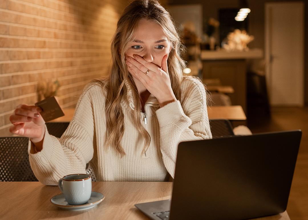 Young woman in shock by credit card information online.