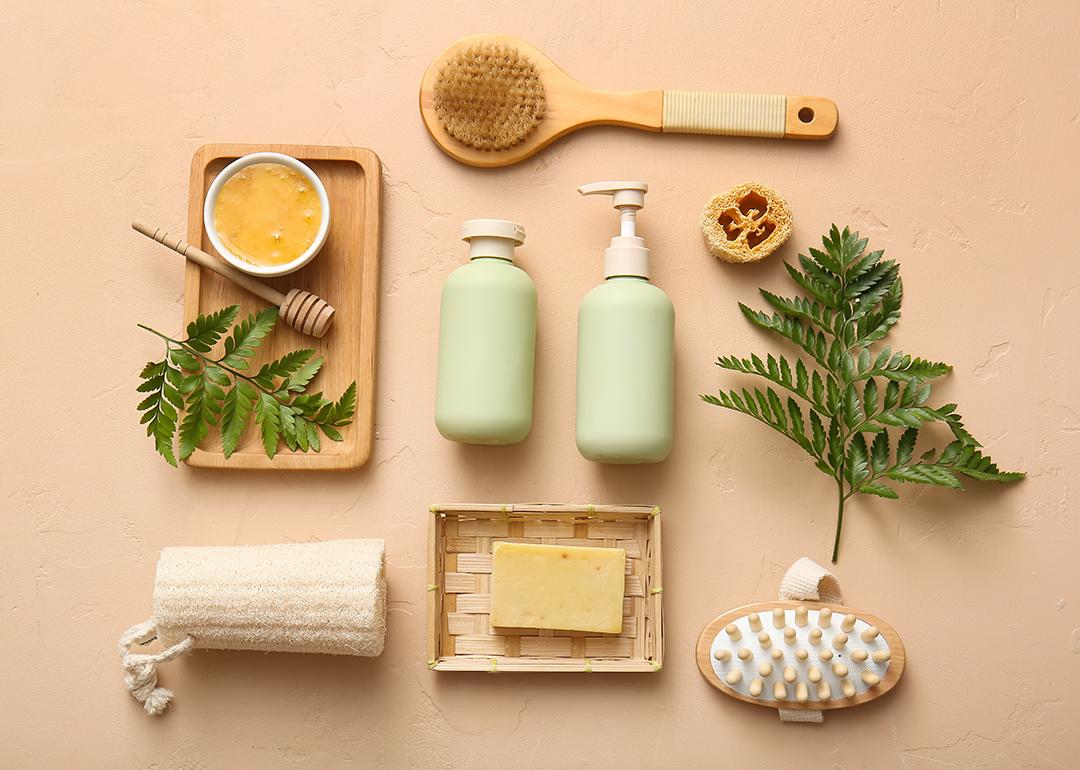 Soap, body scrub, brushes and bathroom essentials laid on a beige surface.