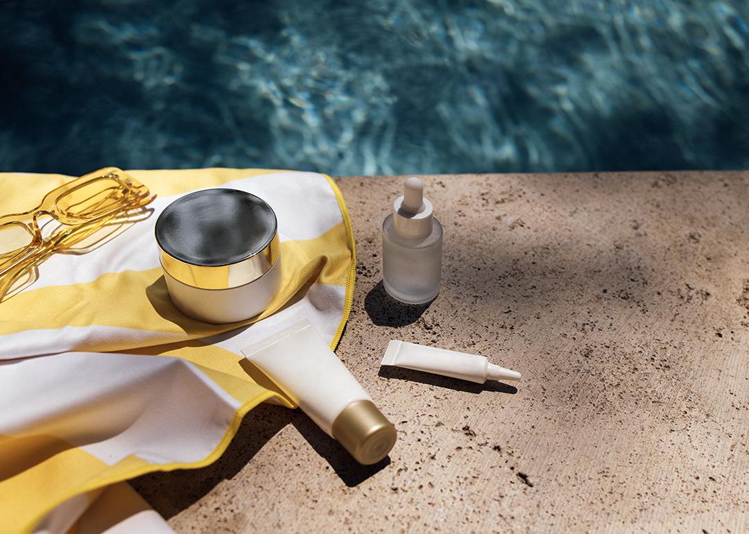 Skincare items in a towel next to a swimming pool. 