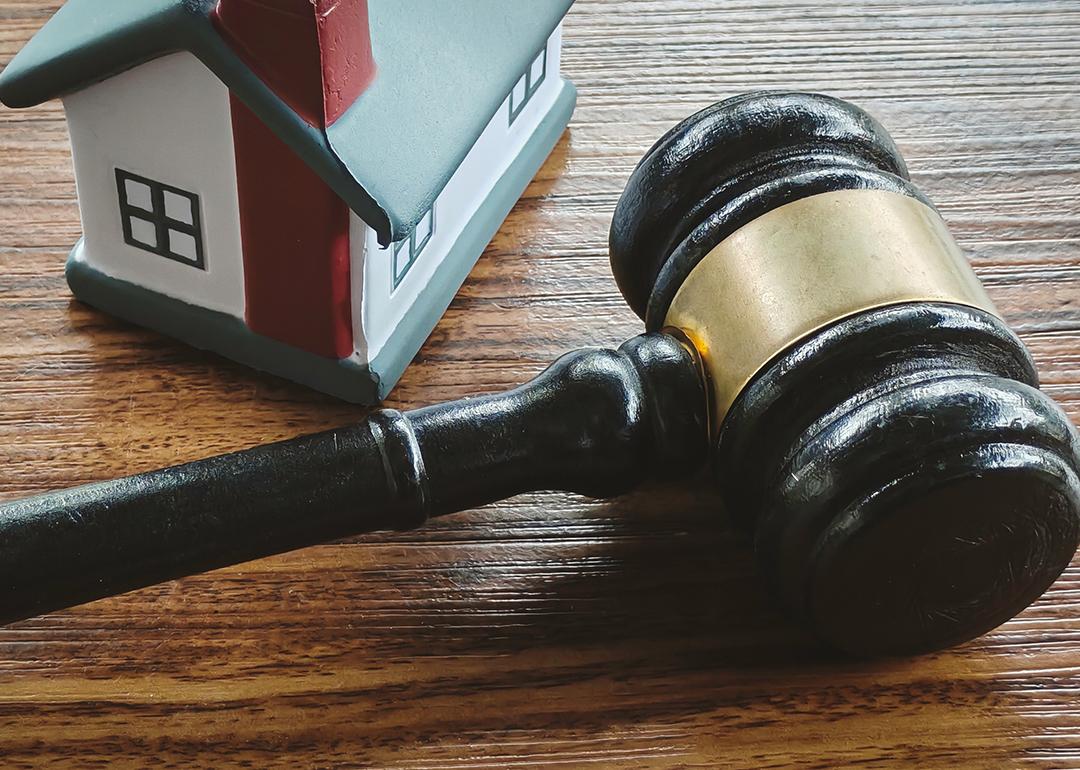 A miniature house and a gavel in a wooden surface.
