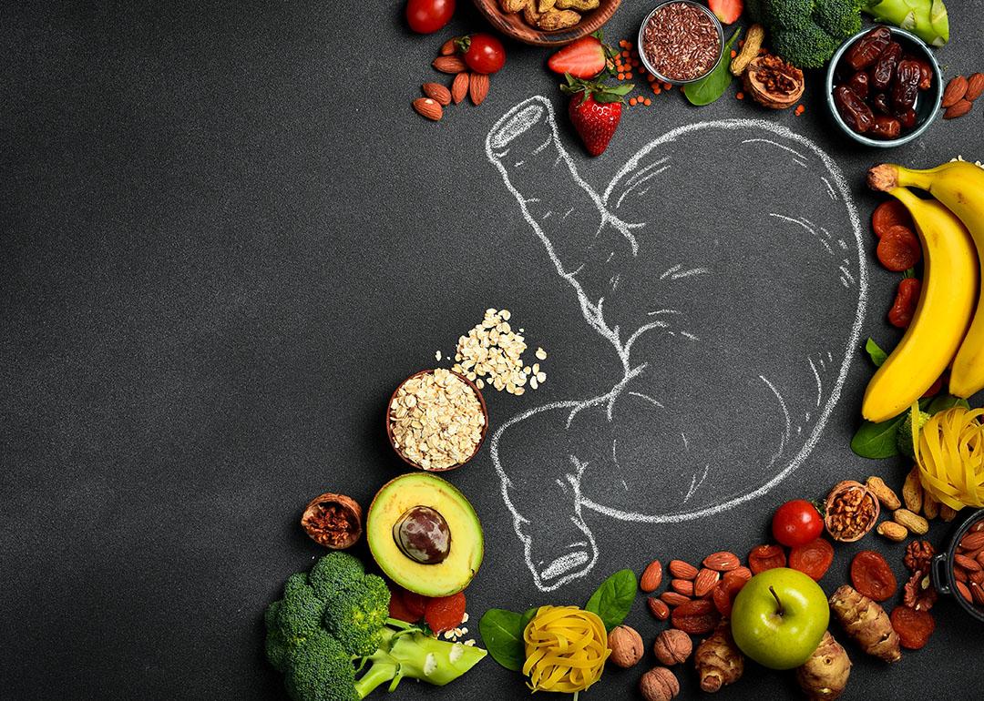 Fresh fruits and vegetables surrounding a drawing of the digestive system.