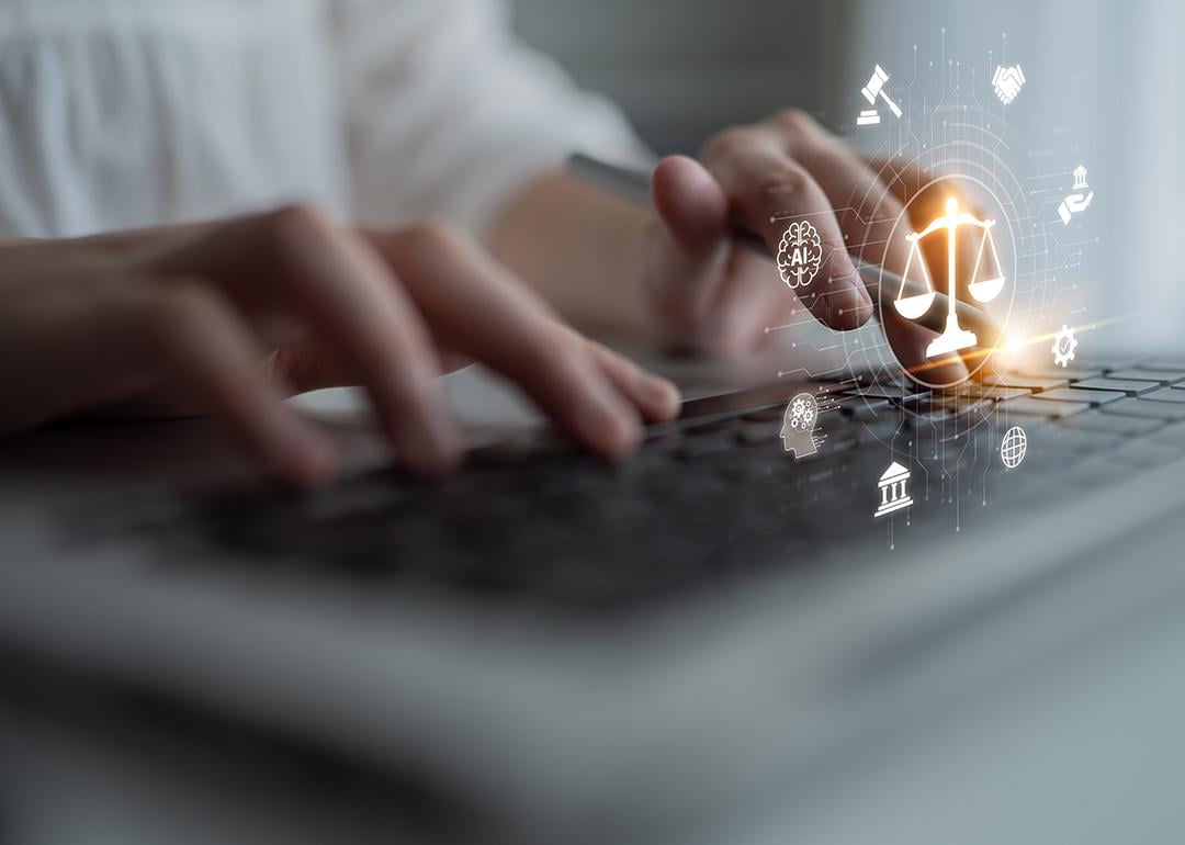A person using a laptop that shows a futuristic justice scale with digital law interface.