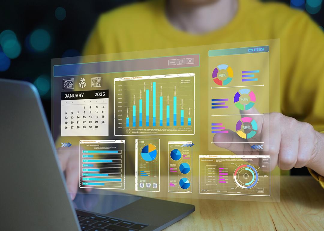 Set of business intelligence dashboard graphics over a person working on a laptop.