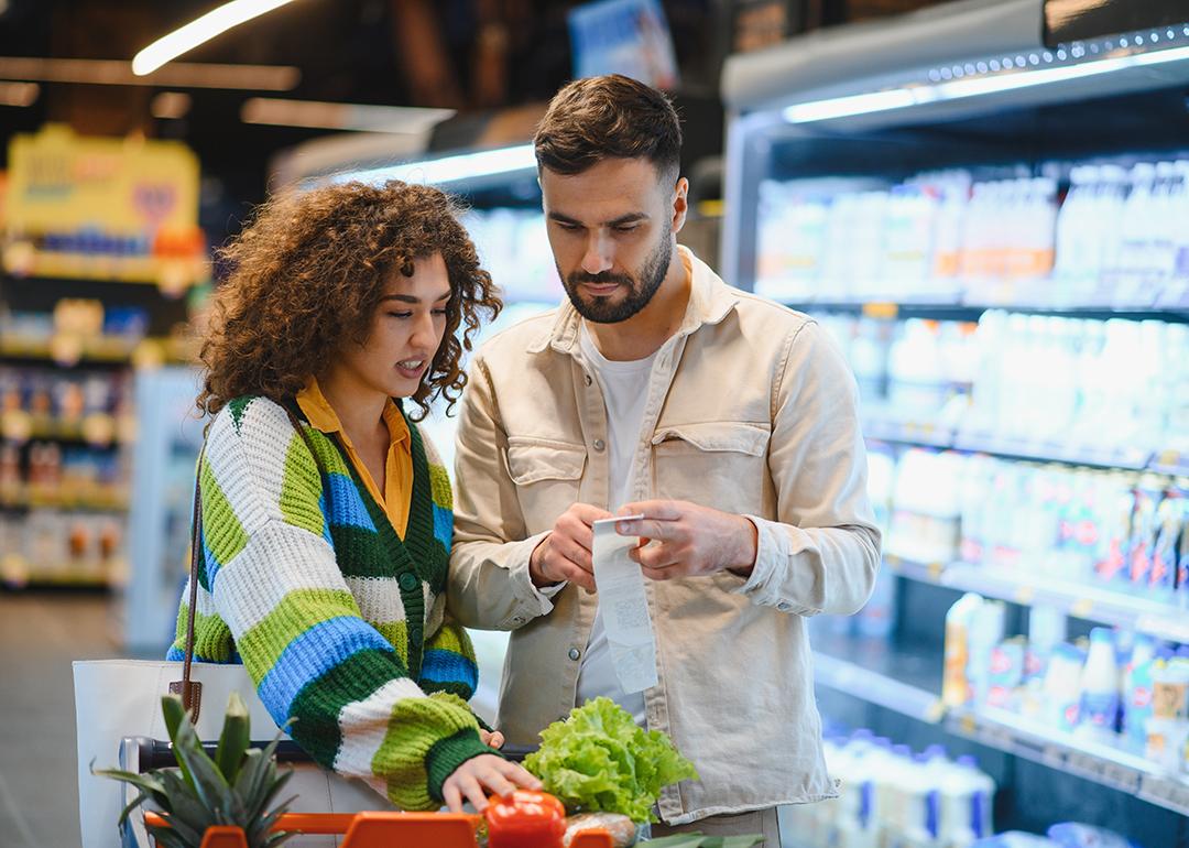A young couple looking at their list while grocery shopping.