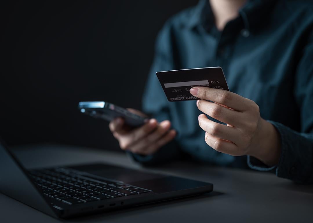 A person checking credit card details from a smartphone and laptop.