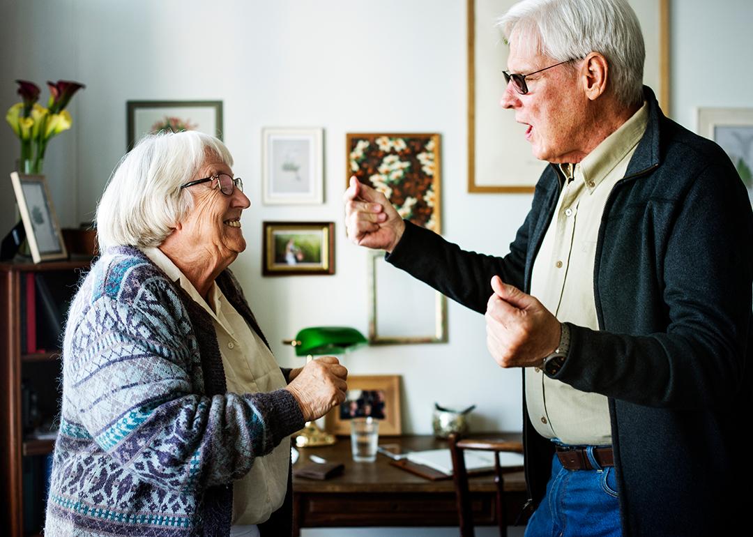 A senior couple dancing together at home.
