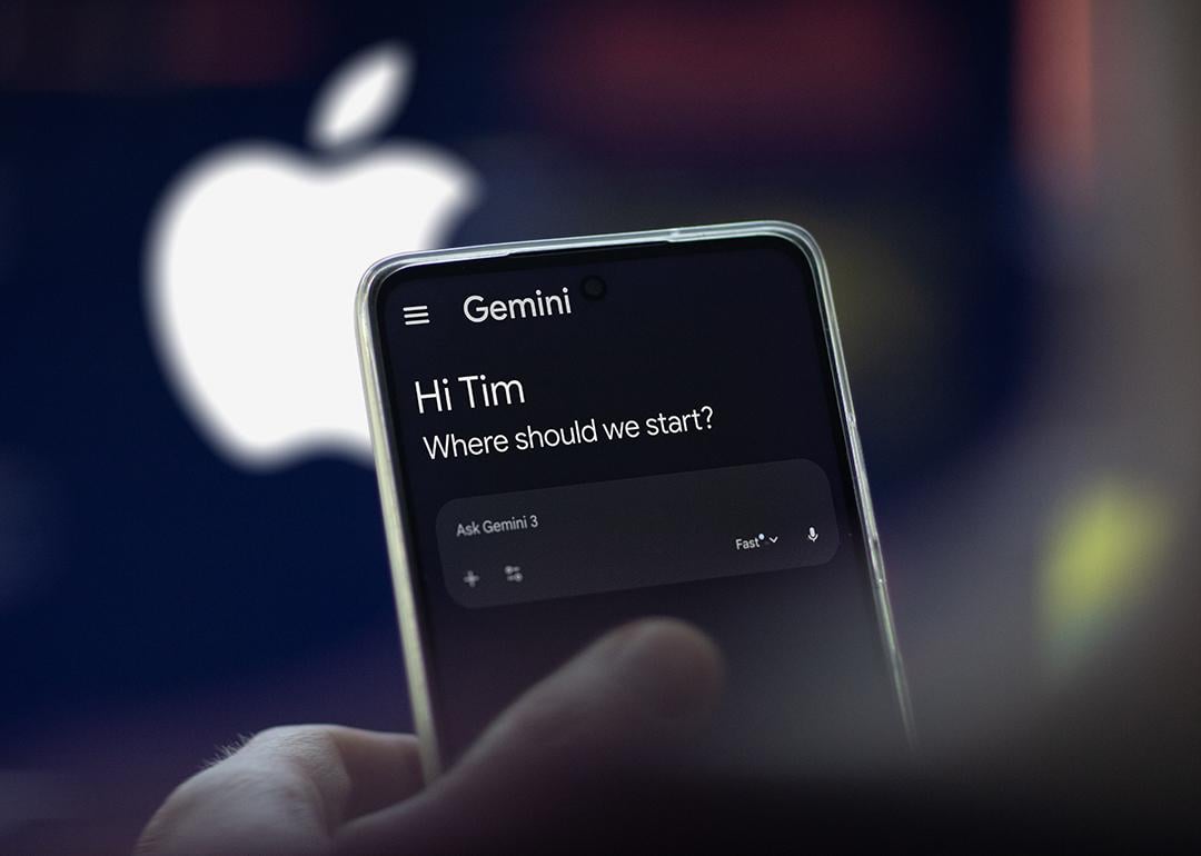 The Gemini app on a phone, with a blurred logo of Apple in the background.