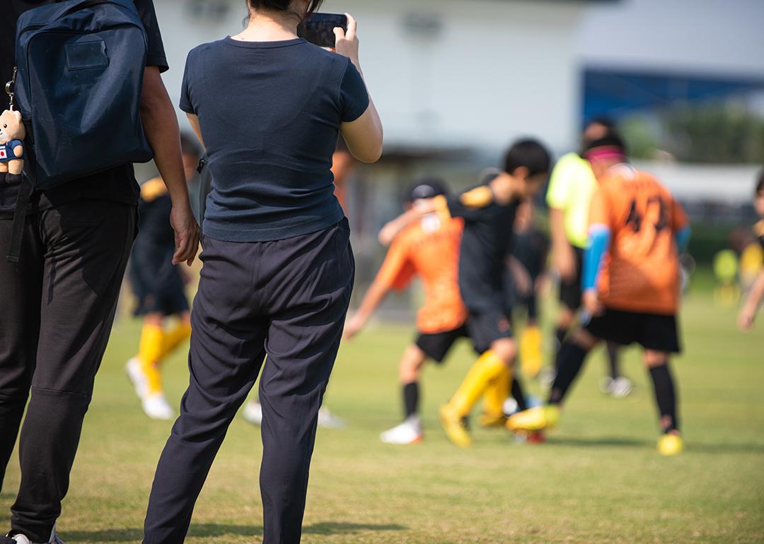 Soccer parents recording their children in a school tournament.