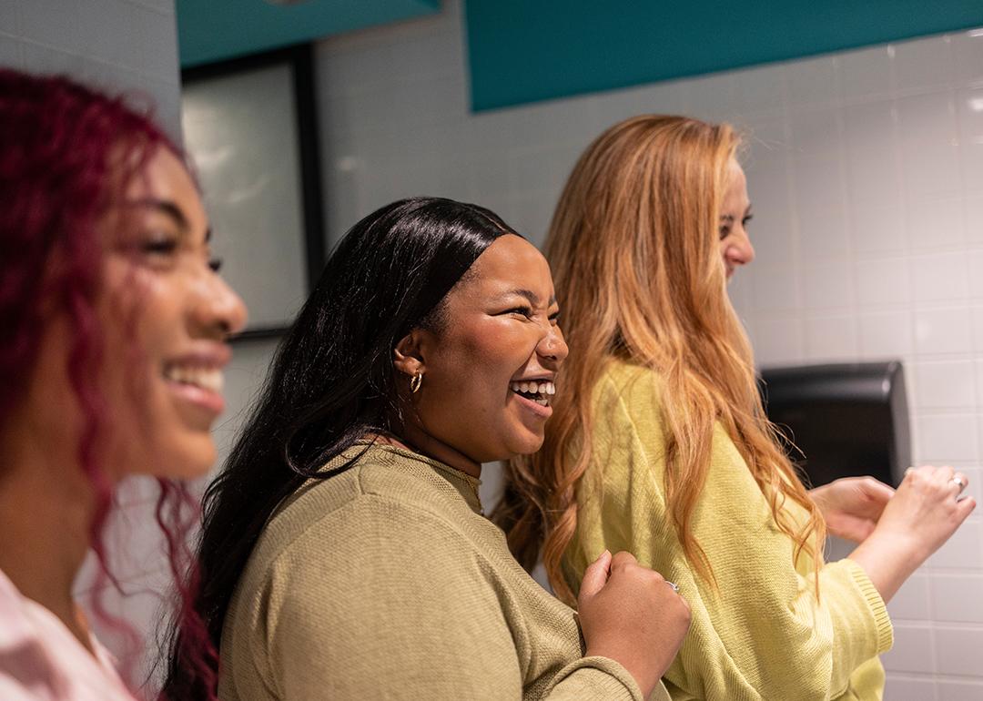 Three young women enjoying a lighthearted moment together in a restroom.