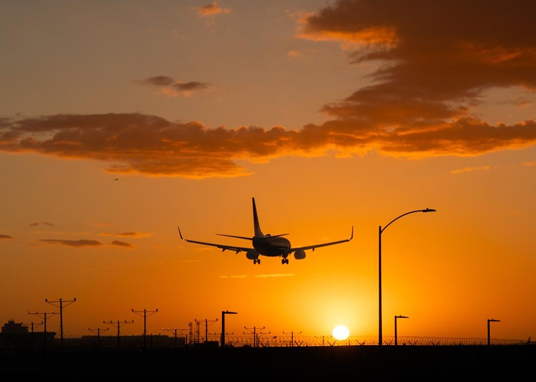 An airplane landing at Los Angeles International Airport during sunset in California, USA.